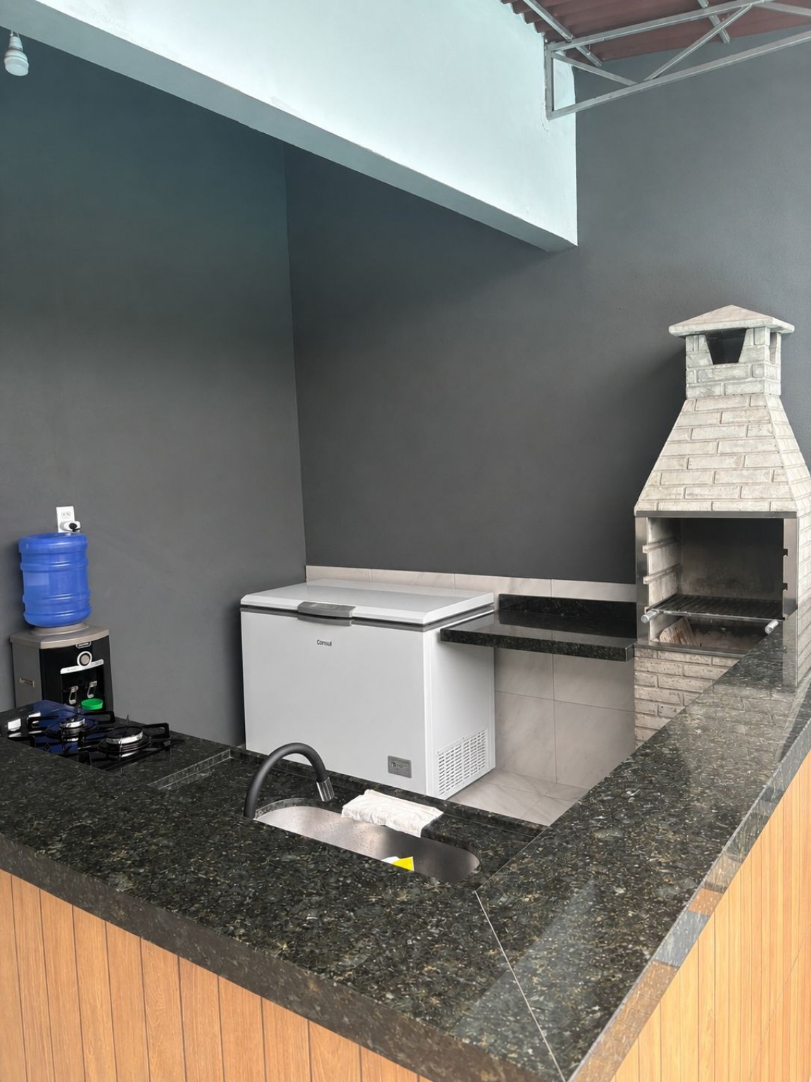 Área gourmet com churrasqueira, bancada e cooktop